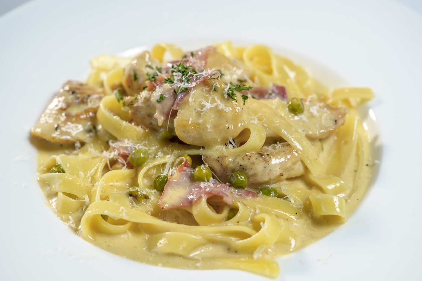 Fettuccine with sauteed chicken breast, prosciutto and fresh peas in garlic cream
