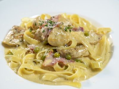 Fettuccine with sauteed chicken breast, prosciutto and fresh peas in garlic cream