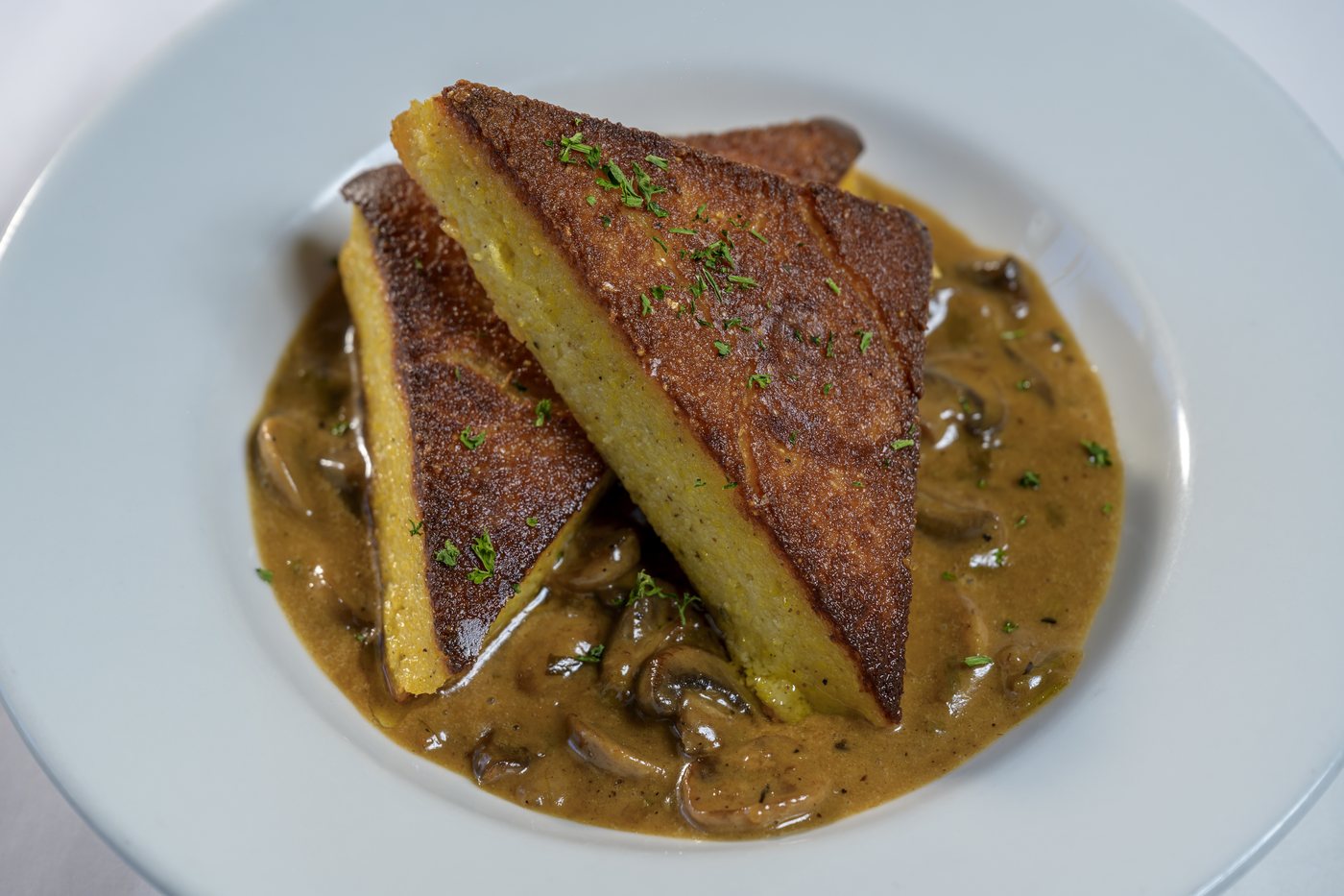 Pan roasted polenta triangles in a wild mushroom brandy sauce