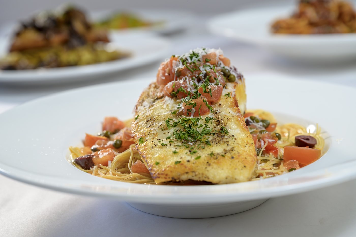 Fresh fish of the day over angel hair with tomatoes, olives and capers