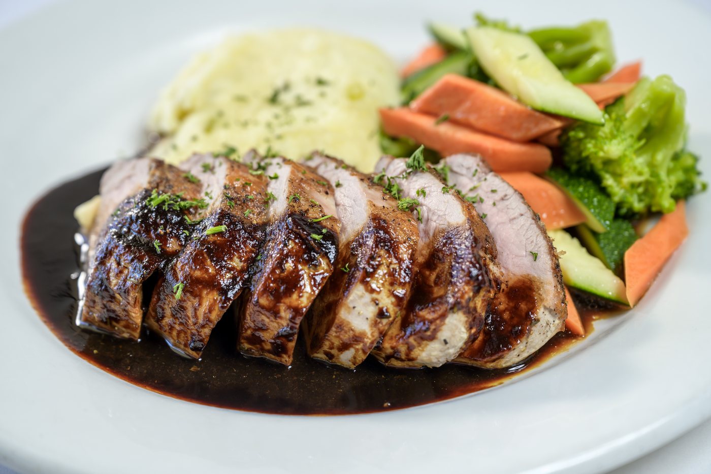 Grilled pork tenderloin with mashed potatoes, vegetables and balsamic chianti reduction