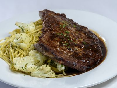 Grilled rib-eye steak with spaghetti, cauliflower and fresh thyme pan-jus