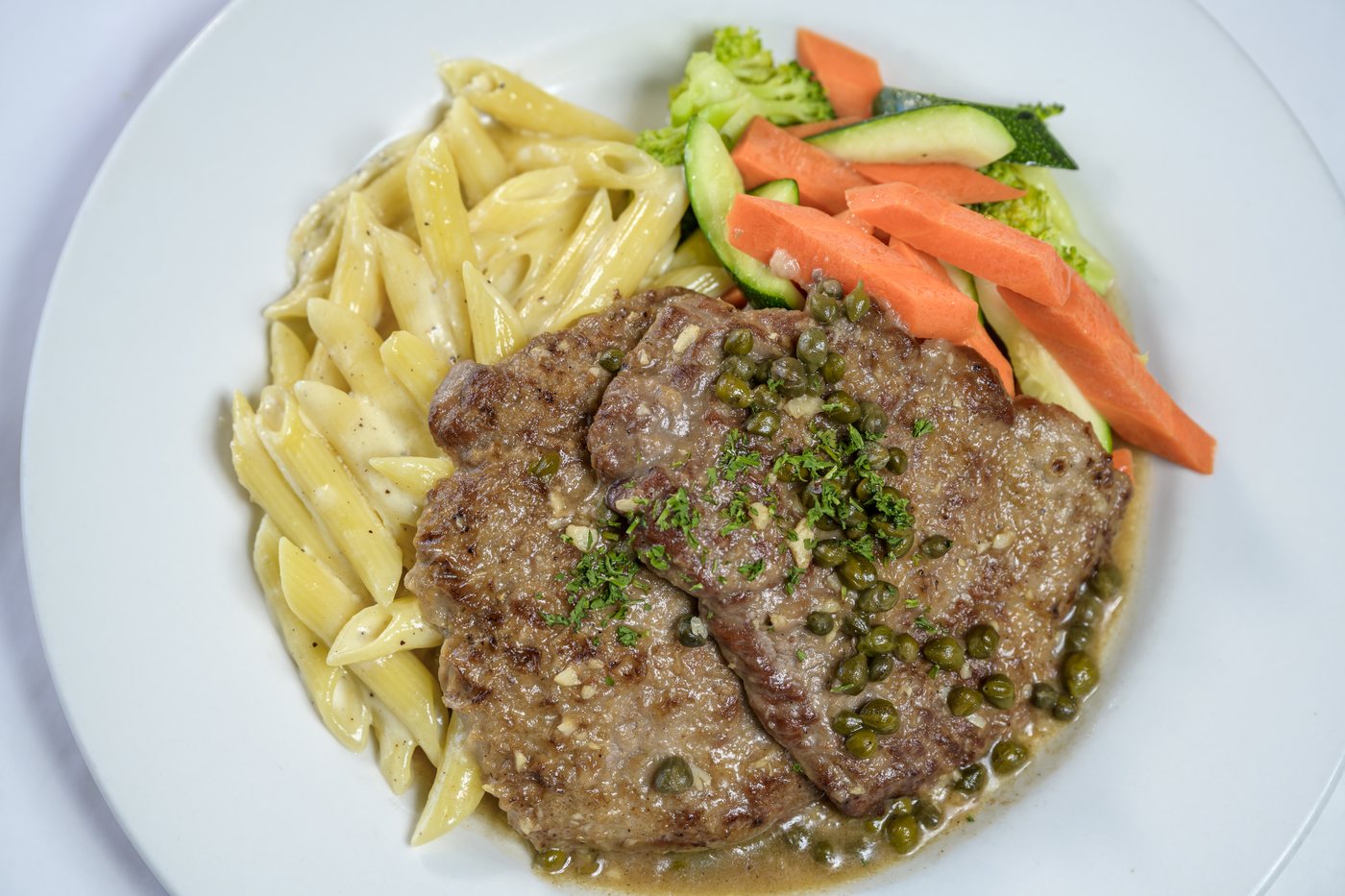 Pan seared veal with capers and lemon butter white wine sauce, penne alfredo and vegetables